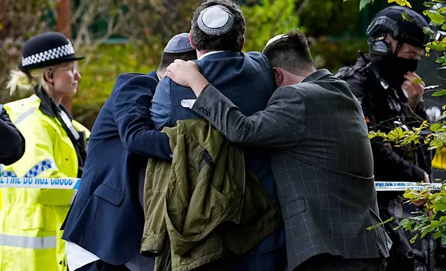 Members of the Jewish community comfort each other near to the Heaton Park Hebrew Congregation synagogue, in Crumpsall, Manchester, England, Thursday, Oct. 2, 2025 after Police reported that two people were killed and three others were seriously injured in a synagogue attack in northern England. (Peter Byrne/PA via AP)