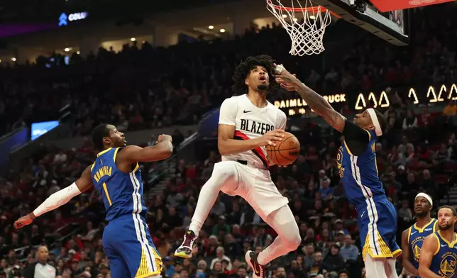 Portland Trail Blazers guard Shaedon Sharpe, center, drives to the basket between Golden State Warriors forward Jonathan Kuminga (1) and guard Gary Payton II (0) during the first half of an NBA basketball game Friday, Oct. 24, 2025, in Portland, Ore. (AP Photo/Amanda Loman)