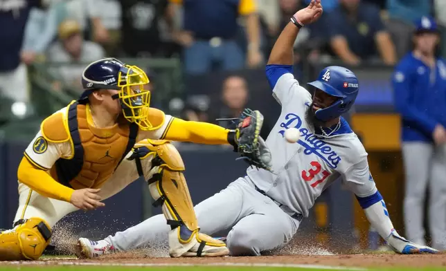 Los Angeles Dodgers' Teoscar Hernández is forced out at home by Milwaukee Brewers catcher William Contreras during the fourth inning in Game 1 of baseball's National League Championship Series, Monday, Oct. 13, 2025, in Milwaukee. (AP Photo/Brynn Anderson)