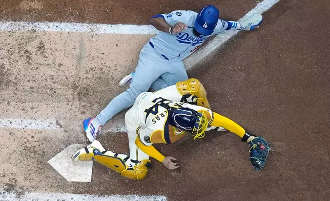 Los Angeles Dodgers' Teoscar Hernández is out at home as Milwaukee Brewers catcher William Contreras takes the throw during the fourth inning of Game 1 of baseball's National League Championship Series Monday, Oct. 13, 2025, in Milwaukee. (AP Photo/Morry Gash)