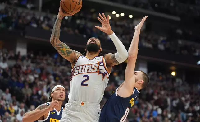 Phoenix Suns center Nick Richards, center, goes up for a basket as Denver Nuggets forwards Aaron Gordon, left, and Christian Braun, right, defend in the first half of an NBA basketball game Saturday, Oct. 25, 2025, in Denver. (AP Photo/David Zalubowski)