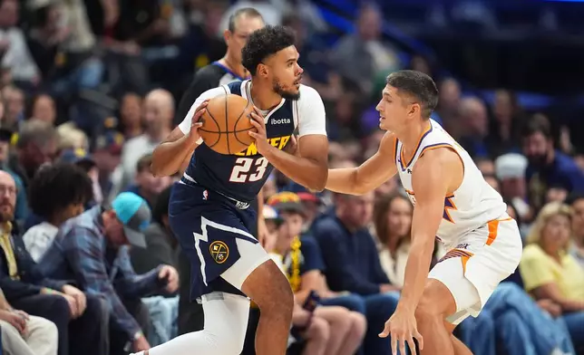 Denver Nuggets forward Cameron Johnson, left, looks to pass the ball as Phoenix Suns guard Grayson Allen, right, defends in the first half of an NBA basketball game Saturday, Oct. 25, 2025, in Denver. (AP Photo/David Zalubowski)