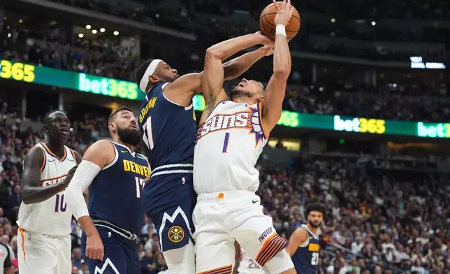 Denver Nuggets guard Bruce Brown, second from front right, fouls Phoenix Suns guard Devin Booker (1) who was driving to the basket in the first half of an NBA basketball game Saturday, Oct. 25, 2025, in Denver. (AP Photo/David Zalubowski)