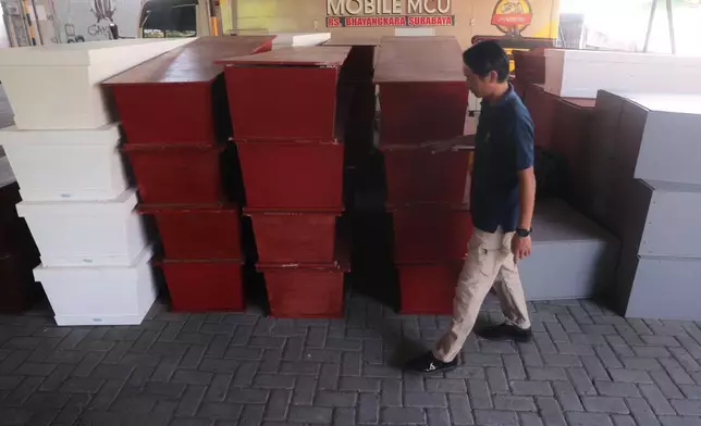 A staff inspects coffins prepared for the victims of a building that collapsed at an Islamic boarding school, at the police hospital in Surabaya, East Java, Indonesia, Sunday, Oct. 5, 2025. (AP Photo/Trisnadi)