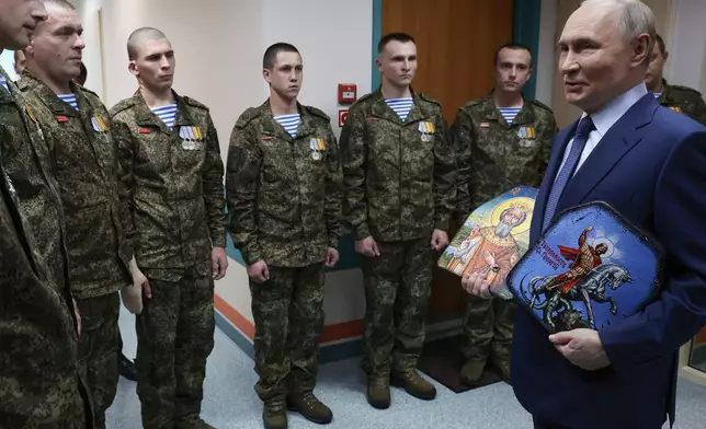 President Vladimir Putin holds Russian Orthodox icons as he meets with soldiers wounded in action in Ukraine, at the the Mandryk Central Military Clinical Hospital, in Moscow, Russia, Wednesday, Oct. 29, 2025. (Vyacheslav Prokofyev, Sputnik, Kremlin Pool Photo via AP)