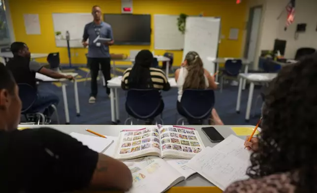 Immigrants trying to learn the English language take notes as Eliezer Guerrero of Catholic Charities of Central Florida teaches an ESOL class, Tuesday, Aug. 19, 2025, in Orlando, Fla. (AP Photo/Rebecca Blackwell)