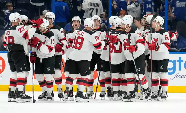 New Jersey Devils players celebratre after defeating the Tampa Bay Lightning during an NHL hockey game Saturday, Oct. 11, 2025, in Tampa, Fla. (AP Photo/Chris O'Meara)