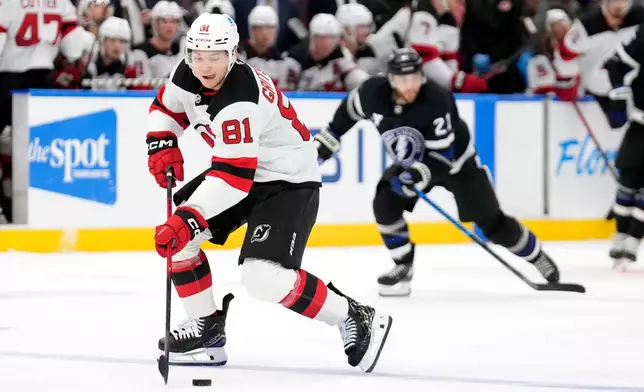 New Jersey Devils right wing Arseny Gritsyuk (81) breaks out ahead of Tampa Bay Lightning center Brayden Point (21) during the third period of an NHL hockey game Saturday, Oct. 11, 2025, in Tampa, Fla. (AP Photo/Chris O'Meara)