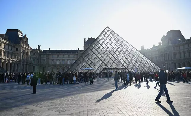People queue to enter the Louvre museum, Thursday, Oct. 30, 2025 in Paris. (AP Photo/Emma Da Silva)
