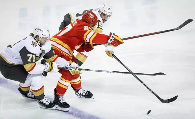 Vegas Golden Knights' William Karlsson, left, and Reilly Smith, right, check Calgary Flames' Matt Coronato during second period of an NHL hockey game in Calgary on Tuesday, Oct. 14, 2025. (Jeff McIntosh/The Canadian Press via AP)