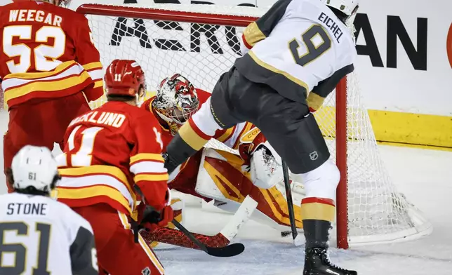 Vegas Golden Knights' Jack Eichel, right, scores on Calgary Flames goalie Dustin Wolf during third period NHL hockey action in Calgary on Tuesday, Oct. 14, 2025. (Jeff McIntosh/The Canadian Press via AP)