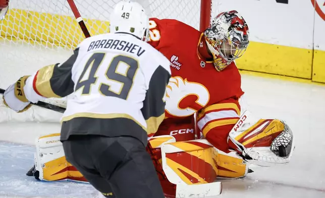 Vegas Golden Knights' Ivan Barbashev (49) has his shot grabbed by Calgary Flames goalie Dustin Wolf during the third period of an NHL hockey game in Calgary, Alberta, on Tuesday, Oct. 14, 2025. (Jeff McIntosh/The Canadian Press via AP)