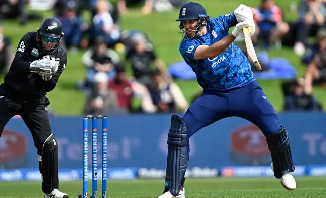 England's Jamie Overton, right, bats in front of New Zealand's Tom Latham during their T20 cricket match in Hamilton, New Zealand, Wednesday, Oct. 29, 2025. (Andrew Cornaga/Photosport via AP)