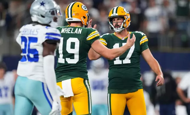 Green Bay Packers' Daniel Whelan (19) and Brandon McManus celebrate a field goal by McManus (17) as Dallas Cowboys cornerback Trikweze Bridges (25) walks past in the second half of an NFL football game Sunday, Sept. 28, 2025, in Arlington, Texas. (AP Photo/Julio Cortez)