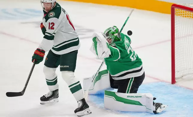 Minnesota Wild left wing Matt Boldy (12) scores a goal on Dallas Stars goaltender Jake Oettinger during the third period of an NHL hockey game Tuesday, Oct. 14, 2025, in Dallas. (AP Photo/Julio Cortez)