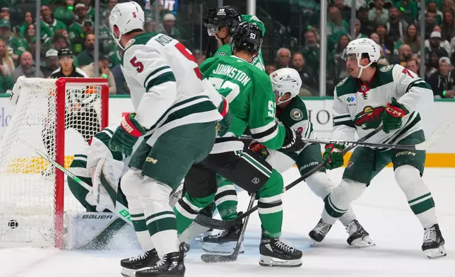 A shot by Dallas Stars center Wyatt Johnston (53) enters the net of Minnesota Wild goaltender Filip Gustavsson for a goal during the first period of an NHL hockey game Tuesday, Oct. 14, 2025, in Dallas. (AP Photo/Julio Cortez)