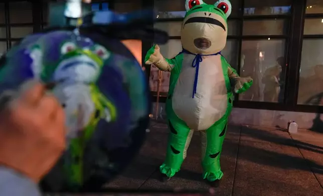 A person paints a portrait of a demonstrator dressed in an inflatable costume outside a United States Immigration and Customs Enforcement (ICE) facility on Tuesday, Oct. 21, 2025, in Portland, Ore. (AP Photo/Jenny Kane)