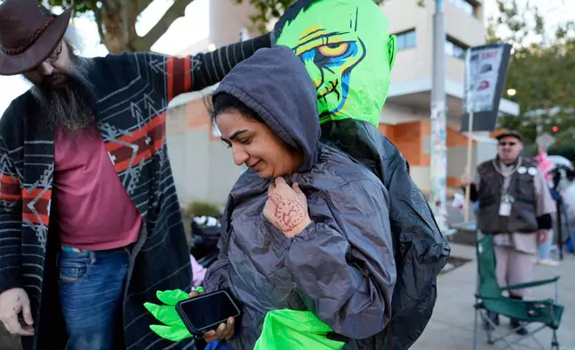 Brooks Brown, Operation Inflation co-founder, left, helps a demonstrator put on an inflatable costume outside a United States Immigration and Customs Enforcement (ICE) facility on Tuesday, Oct. 21, 2025, in Portland, Ore. (AP Photo/Jenny Kane)