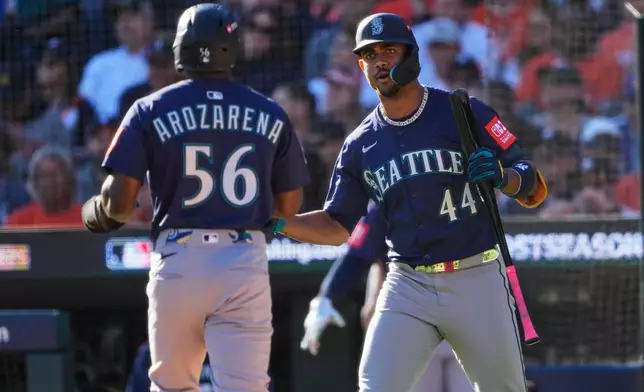Seattle Mariners' Randy Arozarena (56) is congratulated by teammate Julio Rodríguez (44) after scoring during the fifth inning in Game 4 of baseball's American League Division Series against the Detroit Tigers Wednesday, Oct. 8, 2025, in Detroit. (AP Photo/Ryan Sun)