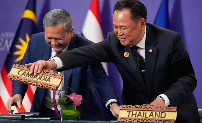 Cambodian Prime Minister Hun Manet, left and Thailand's Prime Minister Anutin Charnvirakul react as they switch country signs during a signing ceremony on the sidelines of the ASEAN Summit in Kuala Lumpur, Malaysia, Sunday, Oct. 26, 2025. (AP Photo/Mark Schiefelbein)
