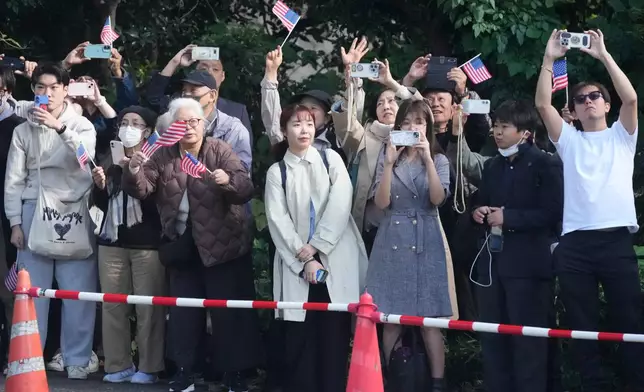 People watch the motorcade of President Donald Trump arriving at the Akasaka Palace in Tokyo, Japan, Tuesday, Oct. 28, 2025. (AP Photo/Mark Schiefelbein)
