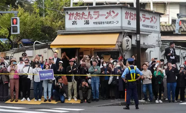 Bystanders look at a motorcade carrying President Donald Trump in Tokyo, Tuesday, Oct. 28, 2025, on his way to the USS George Washington, docked at a U.S. naval base in Yokosuka. (AP Photo/Mark Schiefelbein)