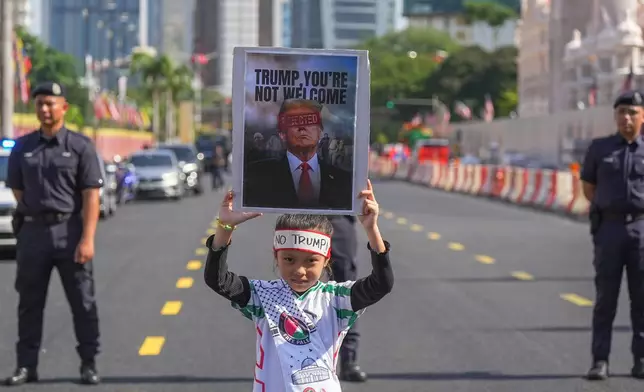 A child holds a sign during a demonstration against U.S. President Donald Trump's attendance at the Association of Southeast Asian Nations (ASEAN) Summit in Kuala Lumpur, Malaysia, on Sunday, Oct. 26, 2025. (AP Photo/Azneal Ishak)