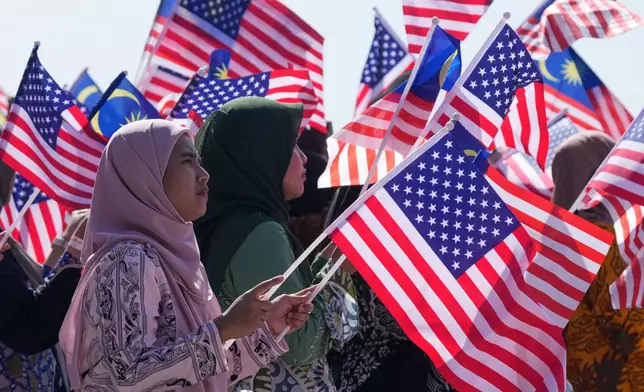 Locals wave Malaysian flags as President Donald Trump arrives at Kuala Lumpur International Airport in Sepang, Malaysia, Sunday, Oct. 26, 2025. (AP Photo/Mark Schiefelbein)