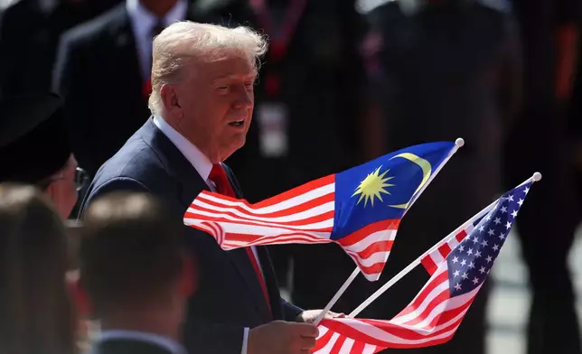 U.S. President Donald Trump holds the Malaysia and U.S. flags during a welcoming ceremony as he arrives at Kuala Lumpur International Airport to attend the 47th Association of Southeast Asian Nations (ASEAN) summit in Kuala Lumpur, Malaysia, Sunday, Oct. 26, 2025. (Hasnoor Hussain/Pool Photo via AP)