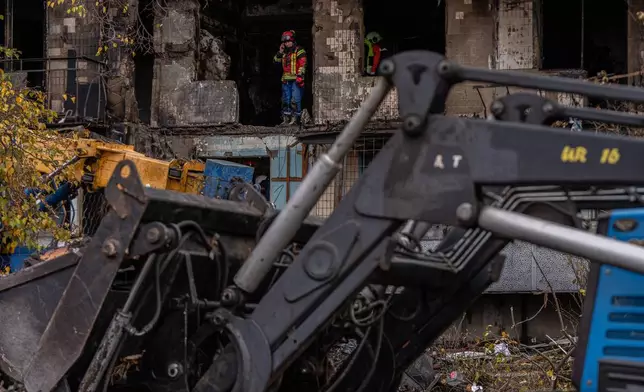 A worker stands inside a damaged apartment building following a Russian attack, Sunday, Oct. 26, 2025, in Kyiv, Ukraine. (AP Photo/Julia Demaree Nikhinson)
