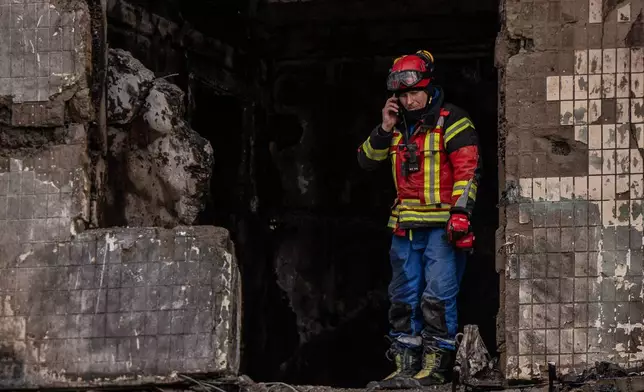 A worker stands inside a damaged apartment building following a Russian attack, Sunday, Oct. 26, 2025, in Kyiv, Ukraine. (AP Photo/Julia Demaree Nikhinson)