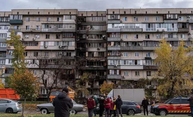 People look at a damaged apartment building following a Russian attack, Sunday, Oct. 26, 2025, in Kyiv, Ukraine. (AP Photo/Julia Demaree Nikhinson)