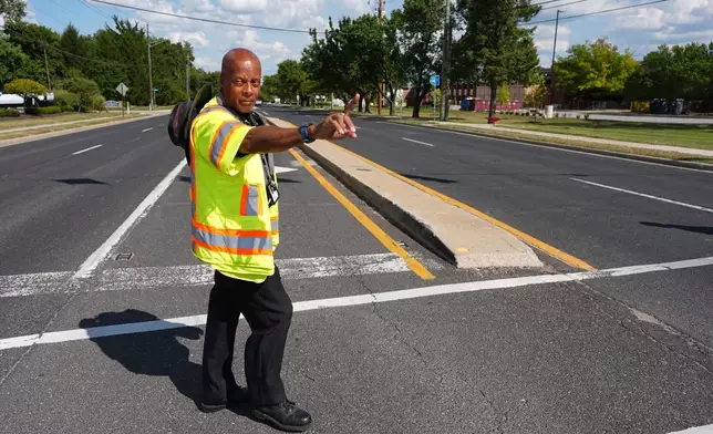 School crossing guard Anthony Taylor directs students on when to cross the street, Wednesday, Sept. 3, 2025, in Indianapolis. (AP Photo/Darron Cummings)