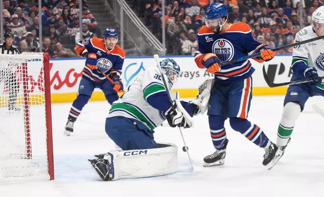 Vancouver Canucks goalie Thatcher Demko (35) makes the save against Edmonton Oilers' Adam Henrique (19) during the second period of an NHL hockey game in Edmonton, Alberta, Saturday, Oct. 11, 2025. (Jason Franson/The Canadian Press via AP)
