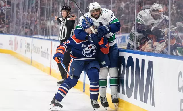 Vancouver Canucks' Evander Kane (91) grabs Edmonton Oilers' Vasily Podkolzin (92) around the head during the third period of an NHL hockey game in Edmonton, Alberta, Saturday, Oct. 11, 2025. (Jason Franson/The Canadian Press via AP)