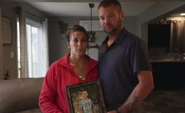 Ashlee and Erik Dahlberg hold a photo of their late son, Liam, in their home in Lowell, Ind., on Tuesday, Aug. 12, 2025. (AP Photo/Laura Bargfeld)
