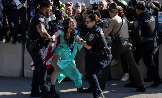 Broadview police officers detain an activist dressed like the Statue of Liberty as dozens of protesters gather near the U.S. Immigration and Customs Enforcement facility in Broadview, Ill., Friday, Oct. 17, 2025. (Ashlee Rezin /Chicago Sun-Times via AP)