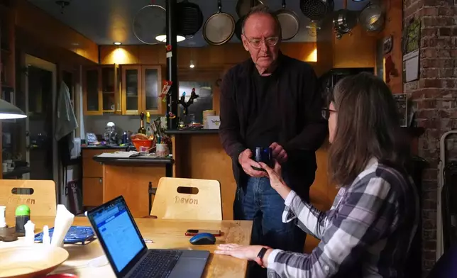 Ross Colquhoun hands his wife Mary E. Brunkow a cup of coffee after hearing about her winning a Nobel Prize in medicine for part of her work on peripheral immune tolerance, in Seattle, Monday, Oct. 6, 2025. (AP Photo/Lindsey Wasson)