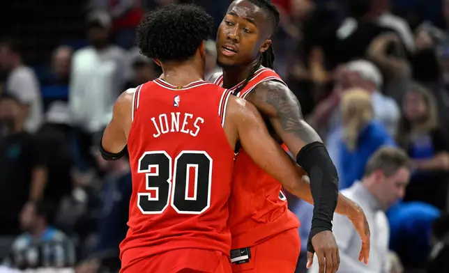 Chicago Bulls guard Tre Jones (30) and guard Ayo Dosunmu congratulate each other after a win against the Orlando Magic in an NBA basketball game, Saturday, Oct. 25, 2025, in Orlando, Fla. (AP Photo/Phelan M. Ebenhack)
