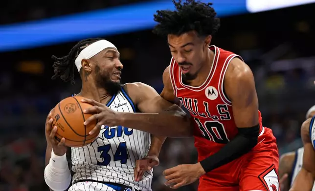 Orlando Magic center Wendell Carter Jr. (34) grabs a rebound in front of Chicago Bulls guard Tre Jones (30) during the second half of an NBA basketball game, Saturday, Oct. 25, 2025, in Orlando, Fla. (AP Photo/Phelan M. Ebenhack)