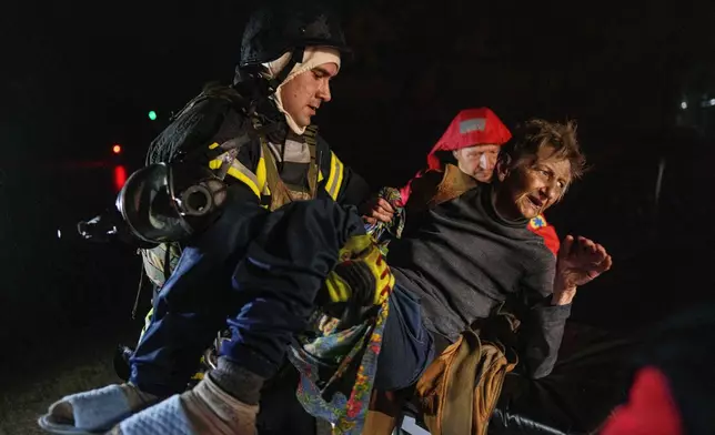 Rescuers carry an injured woman into an ambulance after a Russian strike on a residential neighborhood in Kyiv, Ukraine, on Friday, Oct. 10, 2025. (AP Photo/Evgeniy Maloletka)