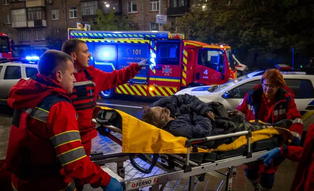Paramedics evacuate an injured woman after a Russian strike on a residential building in Kyiv, Ukraine, Friday, Oct. 10, 2025. (AP Photo/Dan Bashakov)