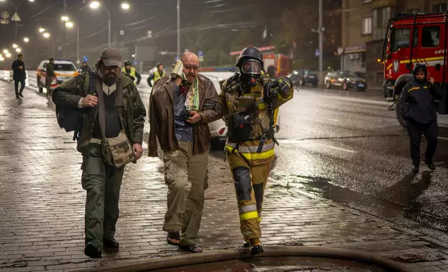 A rescuer helps an injured man after a Russian strike on a residential building in Kyiv, Ukraine, Friday, Oct. 10, 2025. (AP Photo/Dan Bashakov)