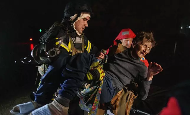 Rescuers carry an injured woman into an ambulance after a Russian strike on a residential neighborhood in Kyiv, Ukraine, on Friday, Oct. 10, 2025. (AP Photo/Evgeniy Maloletka)