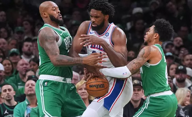 Philadelphia 76ers center Joel Embiid, center, loses control of the ball while trapped by Boston Celtics forward Xavier Tillman, left, guard Anfernee Simons, right, during the first half of an NBA basketball game, Wednesday, Oct. 22, 2025, in Boston. (AP Photo/Charles Krupa)