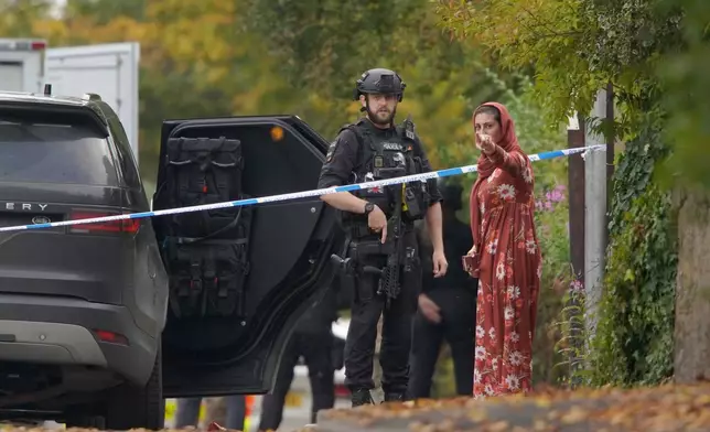 An armed police officer speaks to member of the public near the scene of a stabbing incident at Heaton Park Hebrew Congregation synagogue, in Crumpsall, Manchester, England, Thursday, Oct. 2, 2025. (AP Photo/Ian Hodgson)