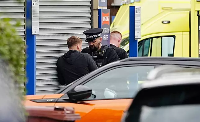 A police officer speaks to a member of the public at the scene of a stabbing at Heaton Park Hebrew Congregation synagogue, in Crumpsall, Manchester, England, Thursday Oct. 2, 2025. (Peter Byrne/PA via AP)