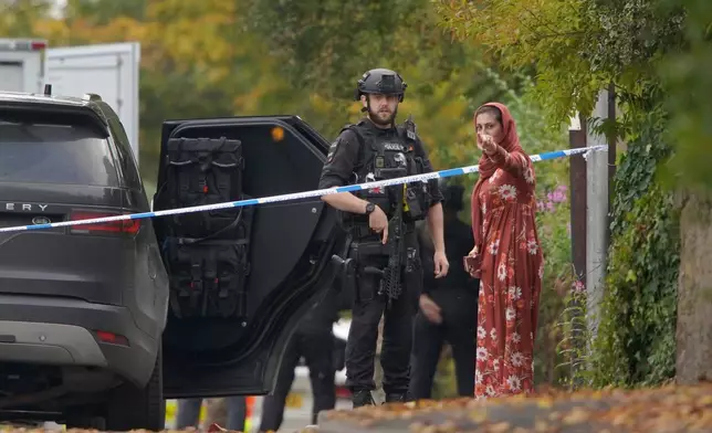 An armed police officer speaks to member of the public near the scene of a stabbing incident at Heaton Park Hebrew Congregation synagogue, in Crumpsall, Manchester, England, Thursday, Oct. 2, 2025. (AP Photo/Ian Hodgson)