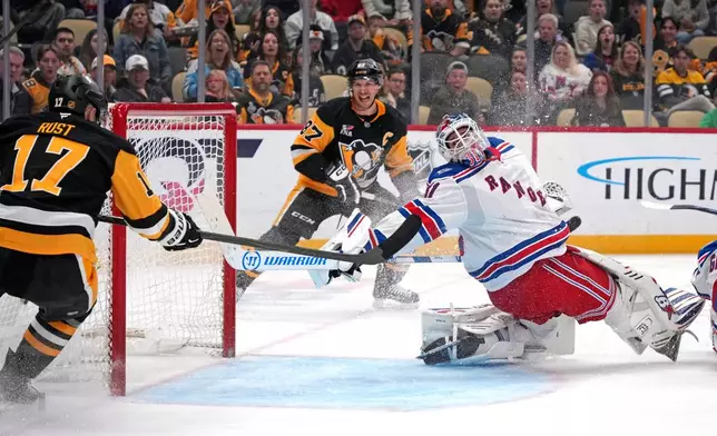 Pittsburgh Penguins' Sidney Crosby, center, and Bryan Rust (17) can't get the puck past New York Rangers goaltender Igor Shesterkin (31) the second period of an NHL hockey game in Pittsburgh, Saturday, Oct. 11, 2025. (AP Photo/Gene J. Puskar)