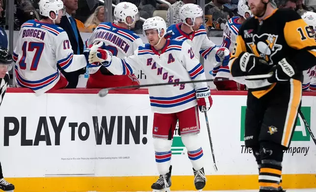 New York Rangers' Adam Fox (23) celebrates as he returns to the bench after scoring the first of his two goals during the second period of an NHL hockey game against the Pittsburgh Penguins in Pittsburgh, Saturday, Oct. 11, 2025. (AP Photo/Gene J. Puskar)